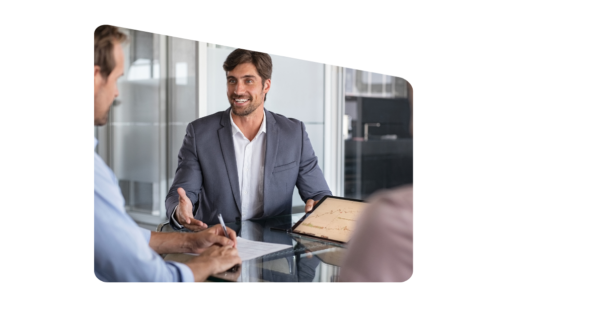 Smiling professional man engaged in a positive discussion with two people across a table, emphasizing collaboration, communication, and teamwork in a business setting.